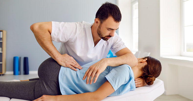 Chiropractor fixing lying womans back in manual therapy