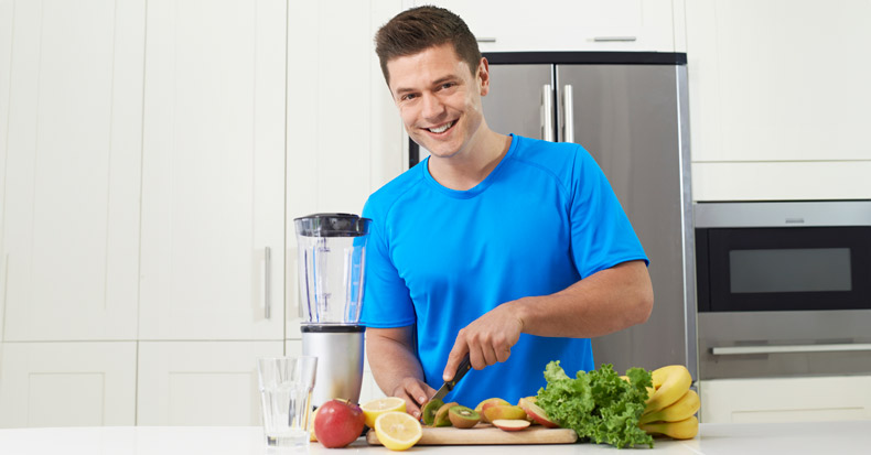 Male Athlete Making Juice Or Smoothie In Kitchen