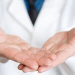 Healthcare professional with open hands symbolizing patient-centered care and support.