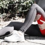 Person holding the back of the thigh due to hamstring pain after physical activity.