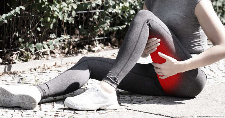 Person holding the back of the thigh due to hamstring pain after physical activity.